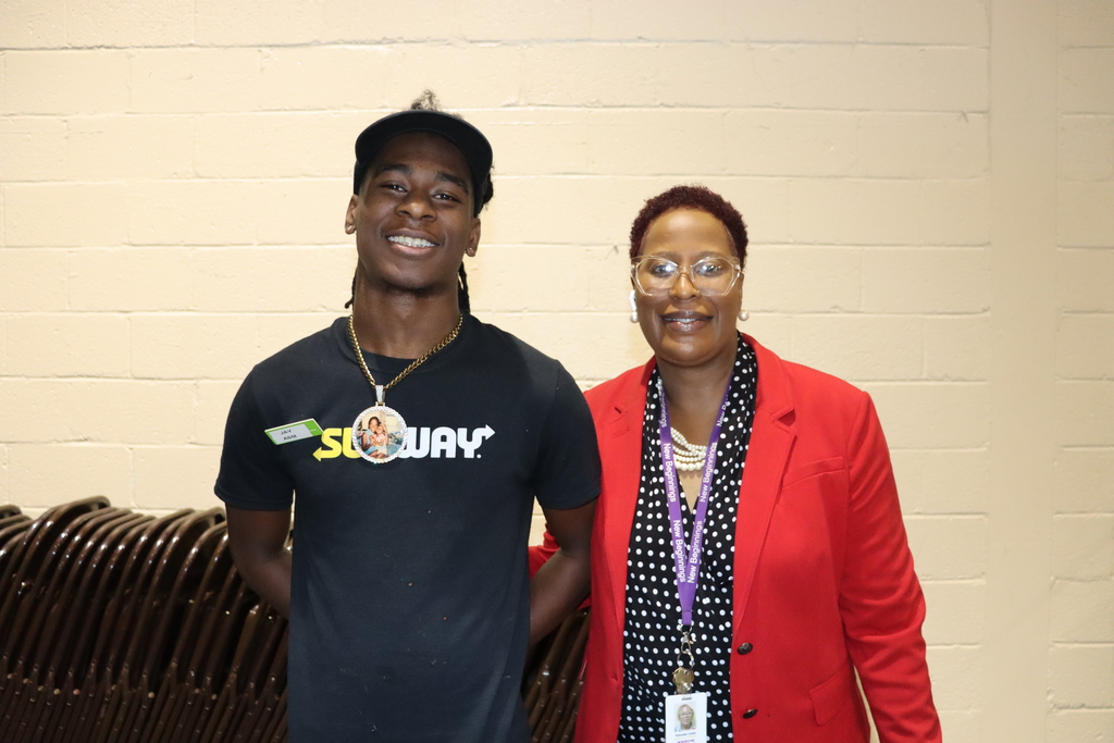 A smiling Subway employee stands beside a woman in a red blazer and polka-dot blouse at the event.