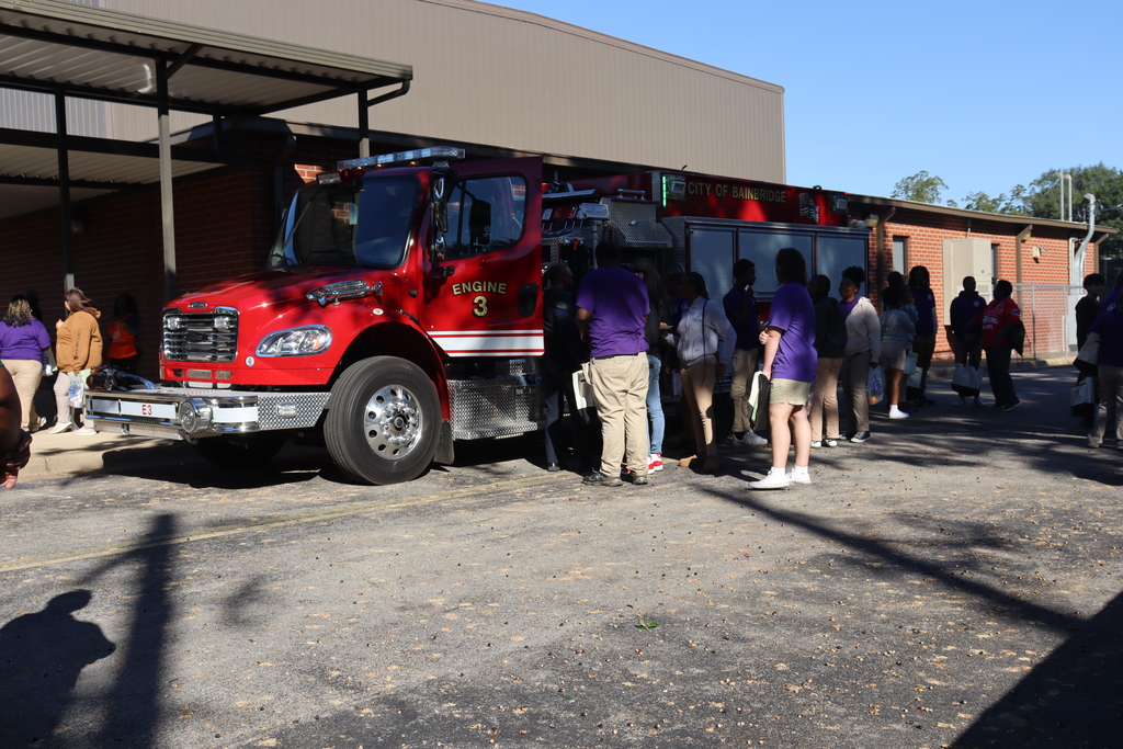 Firefighters and students engage in conversation near a fire truck during a career exploration activity.