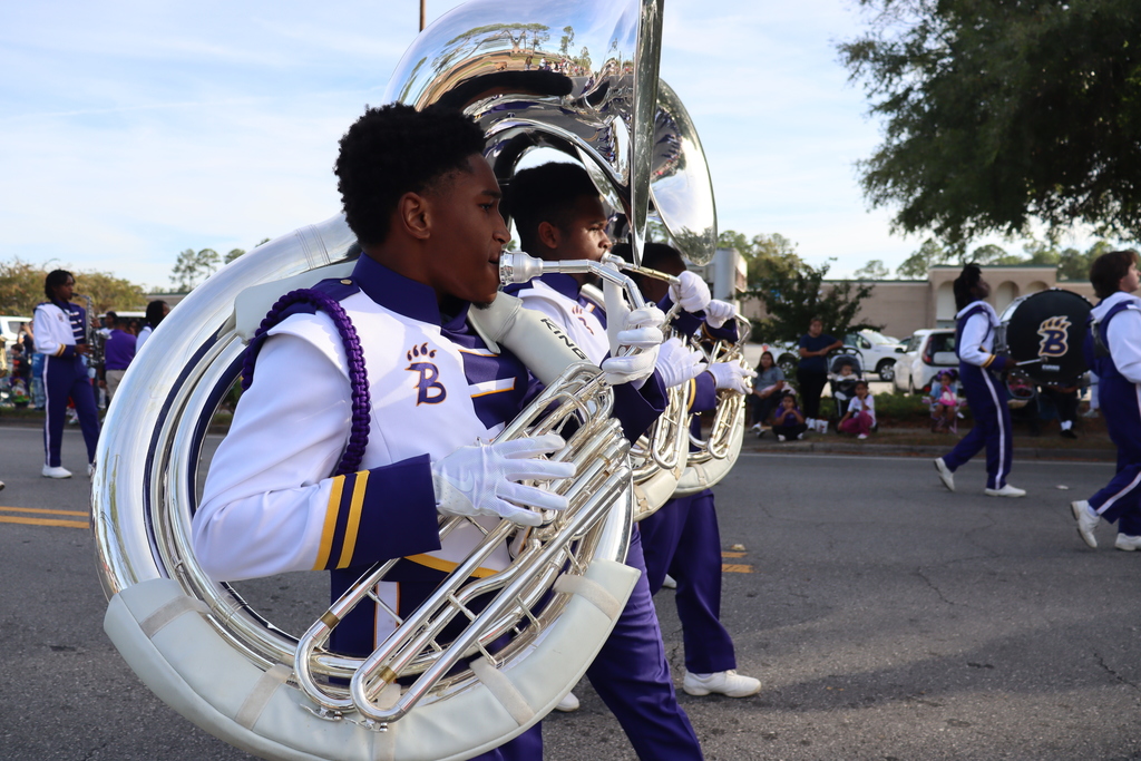 Bainbridge High School marching band musicians play sousaphones while performing in a community parade.