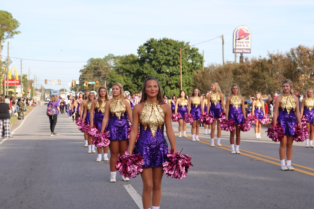 Bainbridge High School band majorettes line up on the street in glittering purple and gold uniforms.