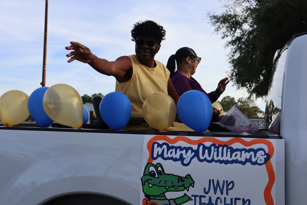 Jones Wheat Primary School teacher Mary Williams rides in a parade truck decorated with blue and gold balloons.