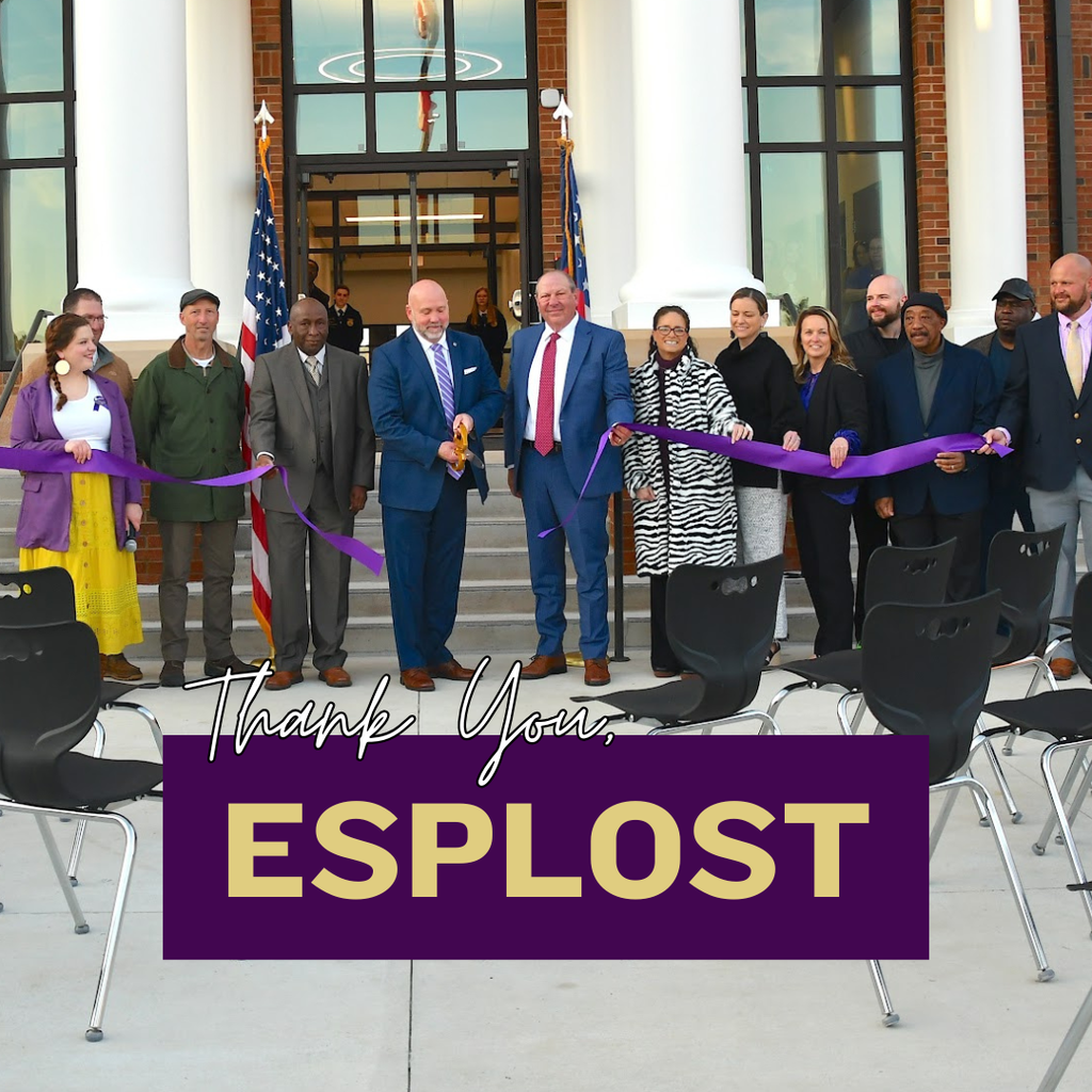 A group of Decatur County School System leaders and community members stand in front of a school building during a ribbon-cutting ceremony, holding a large purple ribbon. The text overlay reads “Thank You, ESPLOST.