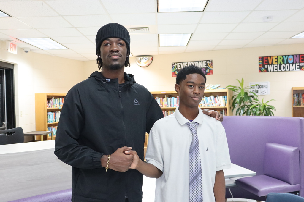 A mentor and student pose together in the library, smiling after the Cuts and Convos session.