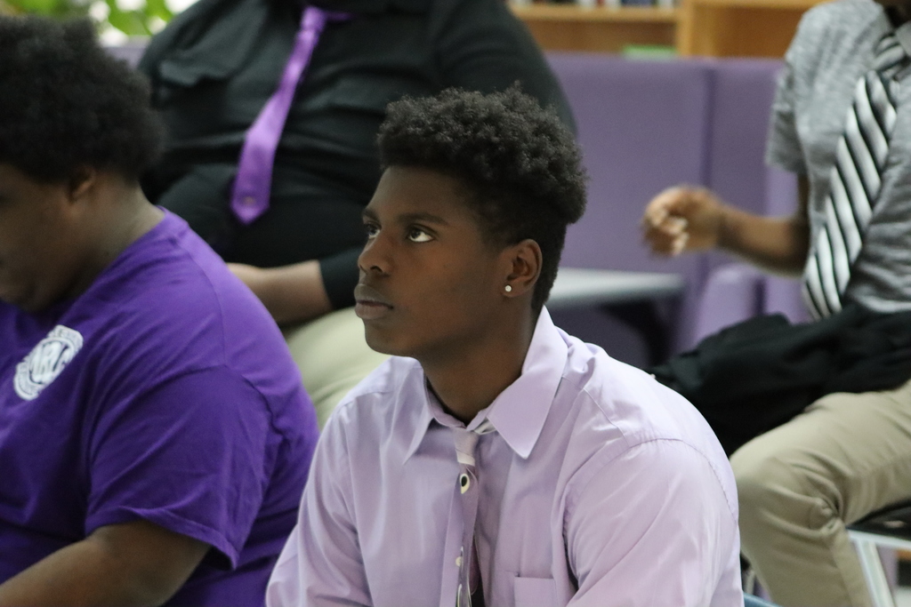 A young man in a light purple shirt and tie listens intently during the Cuts and Convos discussion.
