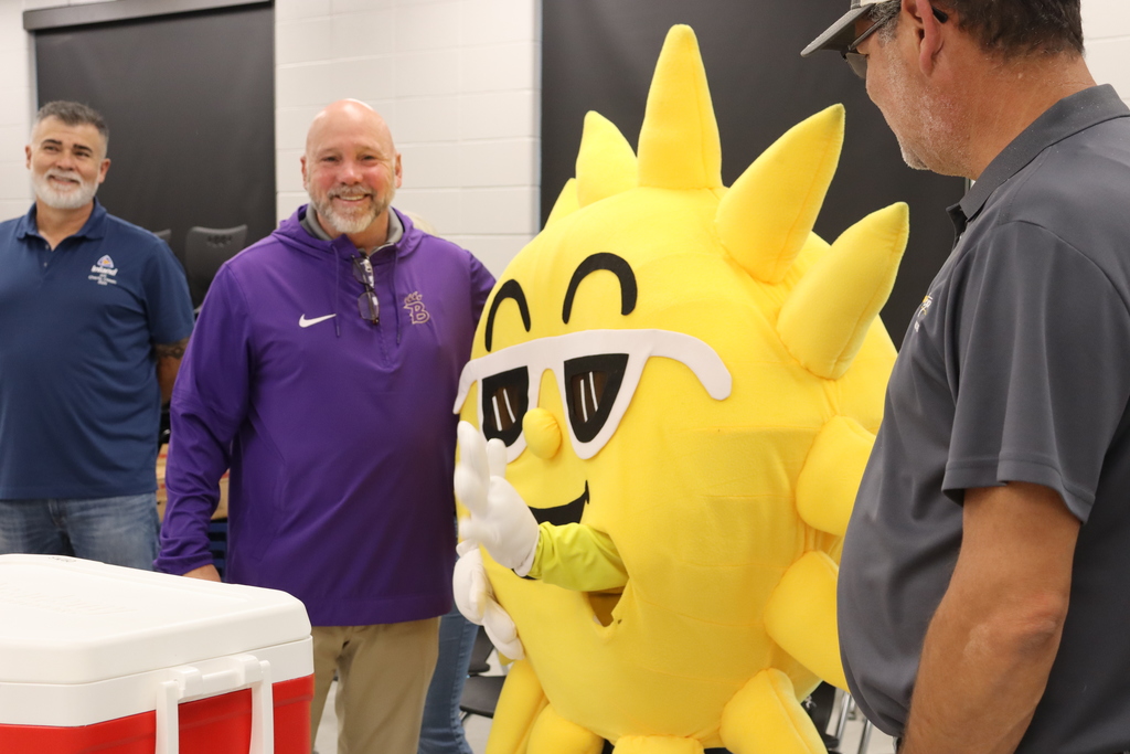 Superintendent Dr. Boyd English smiles alongside Sunny the SunStop mascot and community partners at BMS.