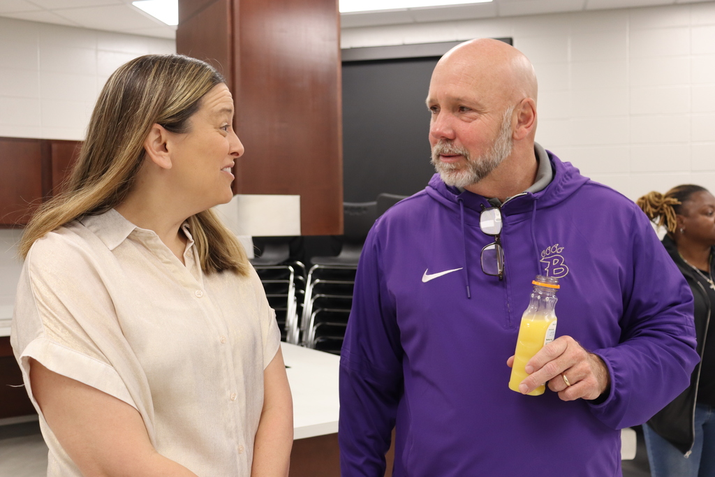 Superintendent Dr. Boyd English chats with a staff member while holding an orange juice bottle.