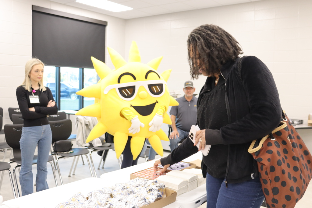 Sunny the SunStop mascot interacts with BMS staff as they grab breakfast items.