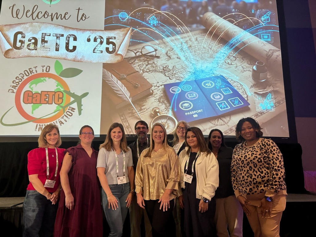 A group of Decatur County educators poses together at the GaETC ’25 conference in front of a “Passport to Innovation” backdrop.