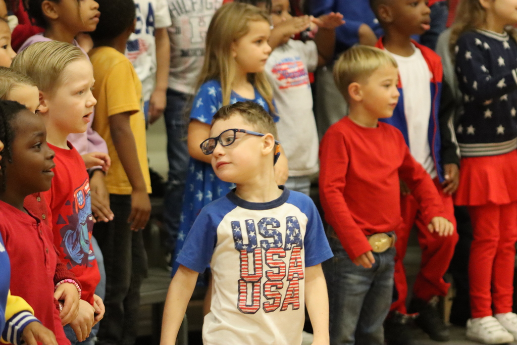 Kindergarten students dressed in red, white, and blue sing together during the Veterans Day program.