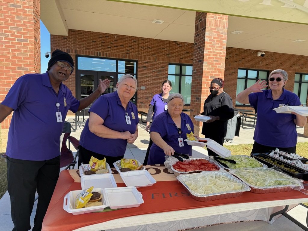 Teachers and staff receive boxed lunches, smiling as they move through the line.