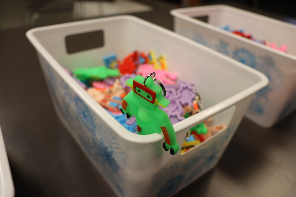 Small plastic bin filled with colorful robot-themed keychains and prizes