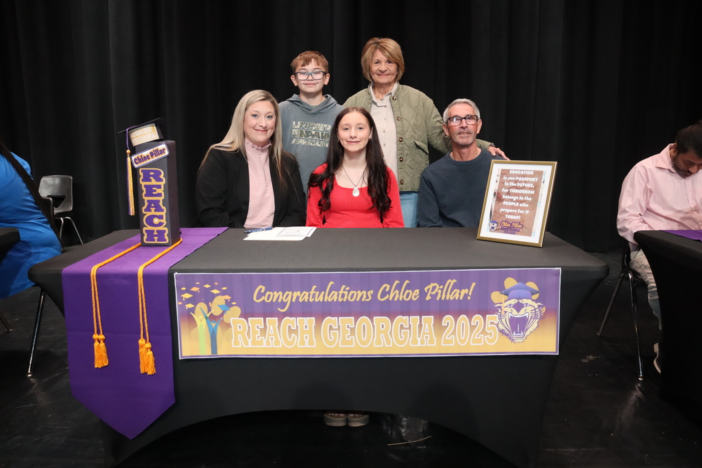 Student seated at a table with family members during a REACH Georgia 2025 scholarship signing ceremony.