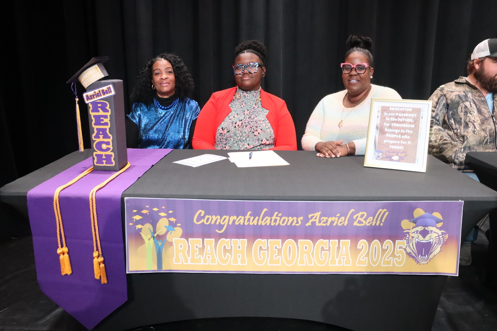Student seated at a table with family members during a REACH Georgia 2025 scholarship signing ceremony.