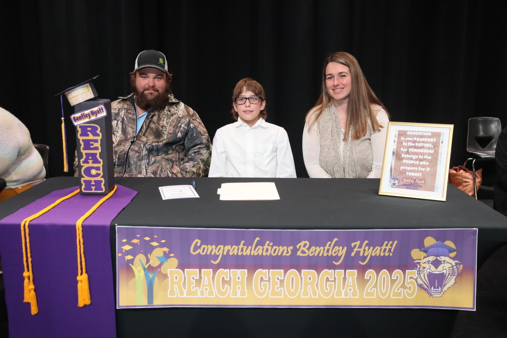 Student seated at a table with family members during a REACH Georgia 2025 scholarship signing ceremony.