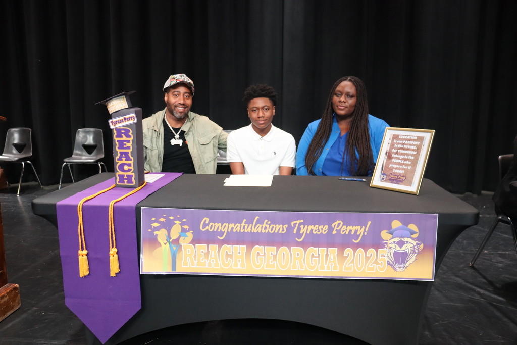 Student seated at a table with family members during a REACH Georgia 2025 scholarship signing ceremony.