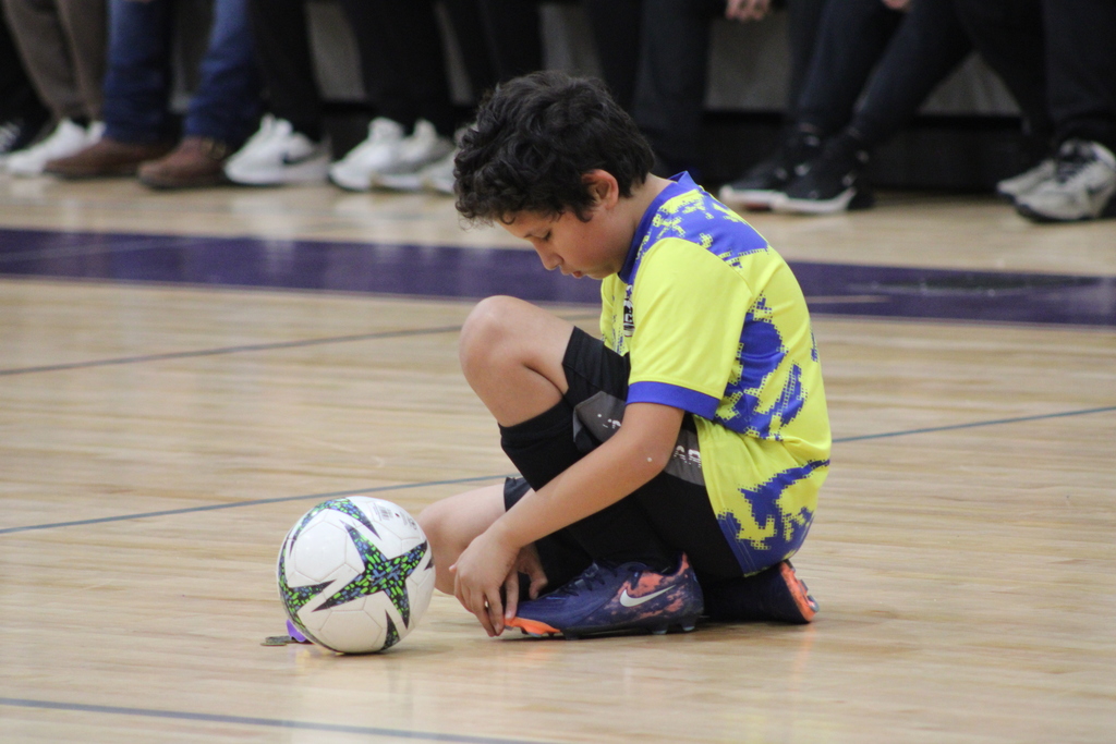 Bainbridge Middle School students participate in a nativity program in the school gym, wearing costumes, kneeling, and standing together as classmates and staff observe.