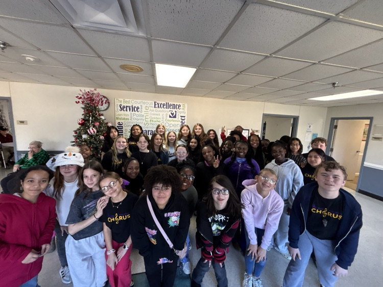 6th grade chorus students posed in front of a Christmas tree