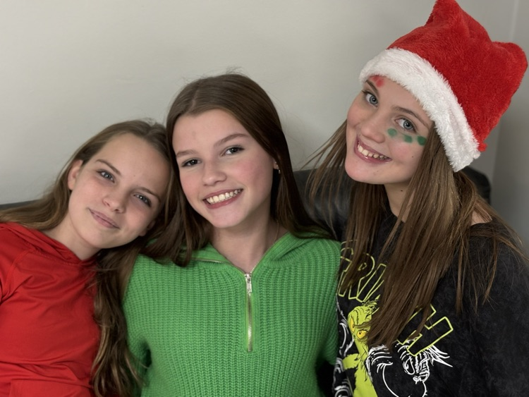 three 7th grade chorus students dressed in festive shirts and Santa hats