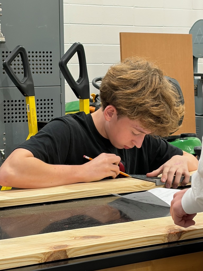 Students measuring and using a speed square to make acuate placement for cuts.
