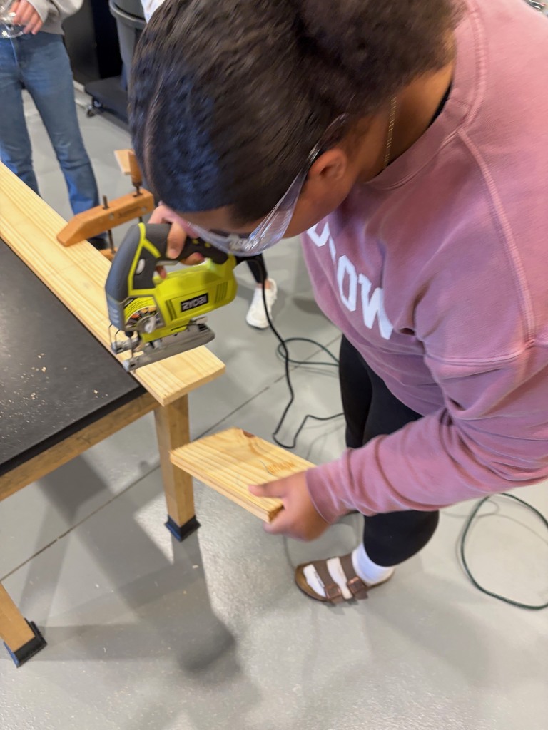 Students using a skill saw to cut a component of the build.