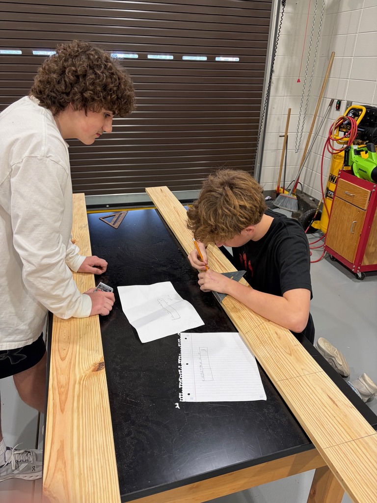 Students working together to read the build plans and make cut marks.