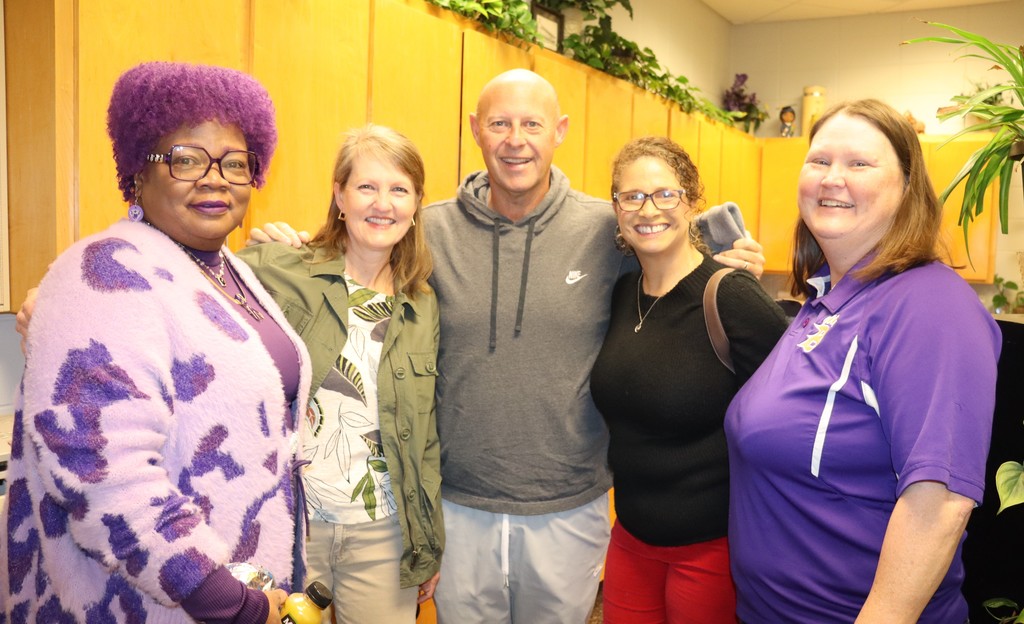 Five smiling staff members stand together indoors, posing for a photo during a school appreciation event.