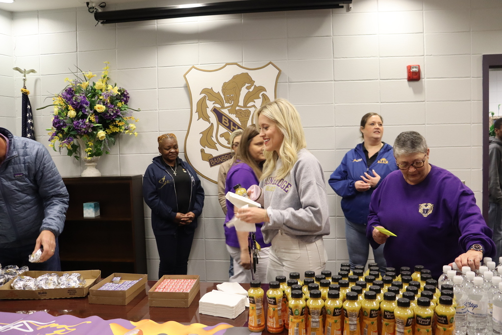 Staff members gather around a table selecting breakfast items during a teacher appreciation event at Bainbridge High School.