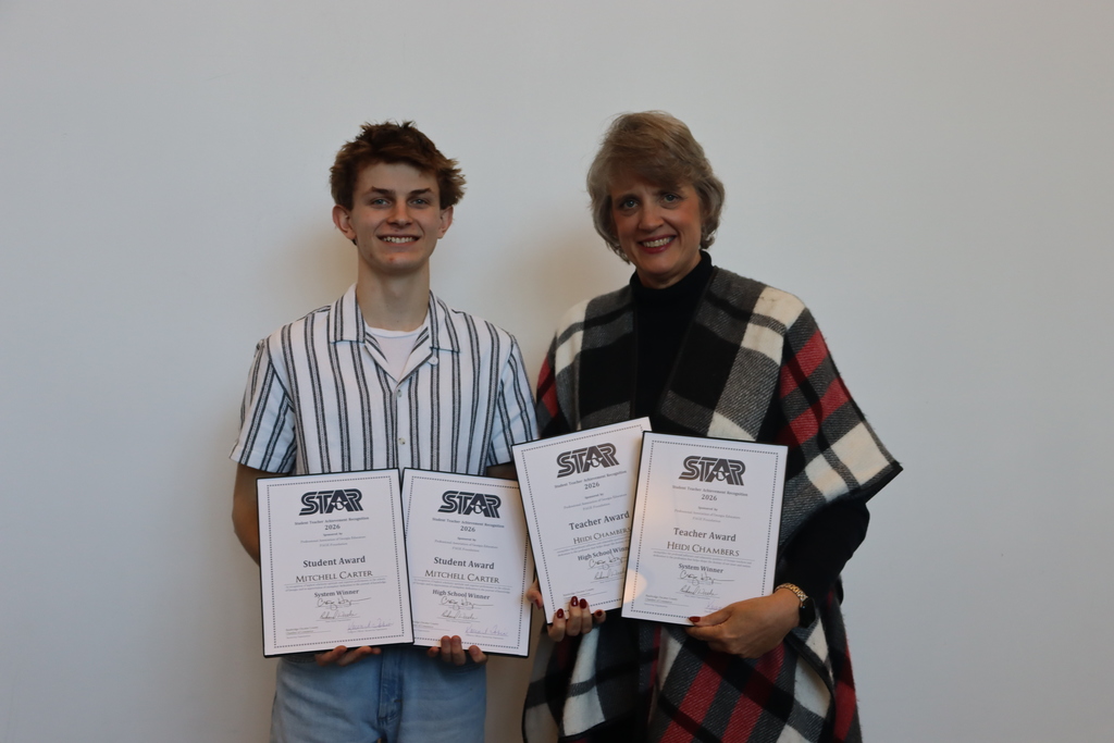 Mitchell Carter and Dr. Heidi Chambers smiling and holding their STAR Student and Teacher Award certificates against a white backdrop.
