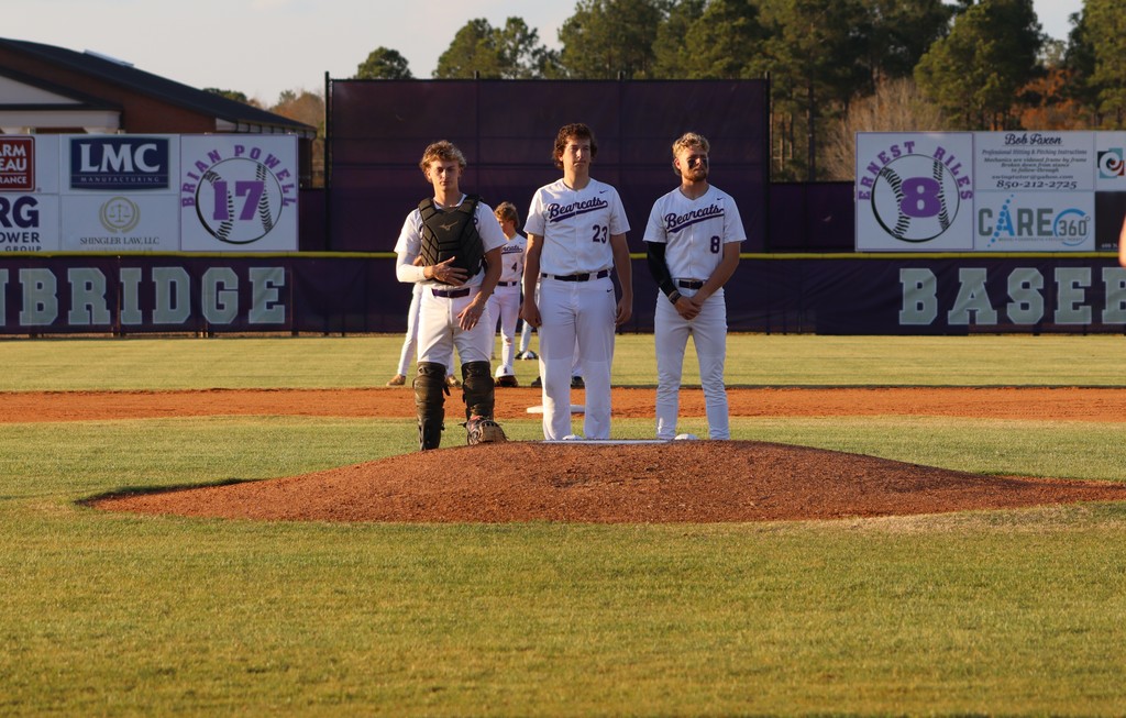 Three Bearcats players stand on the pitcher’s mound before the game.