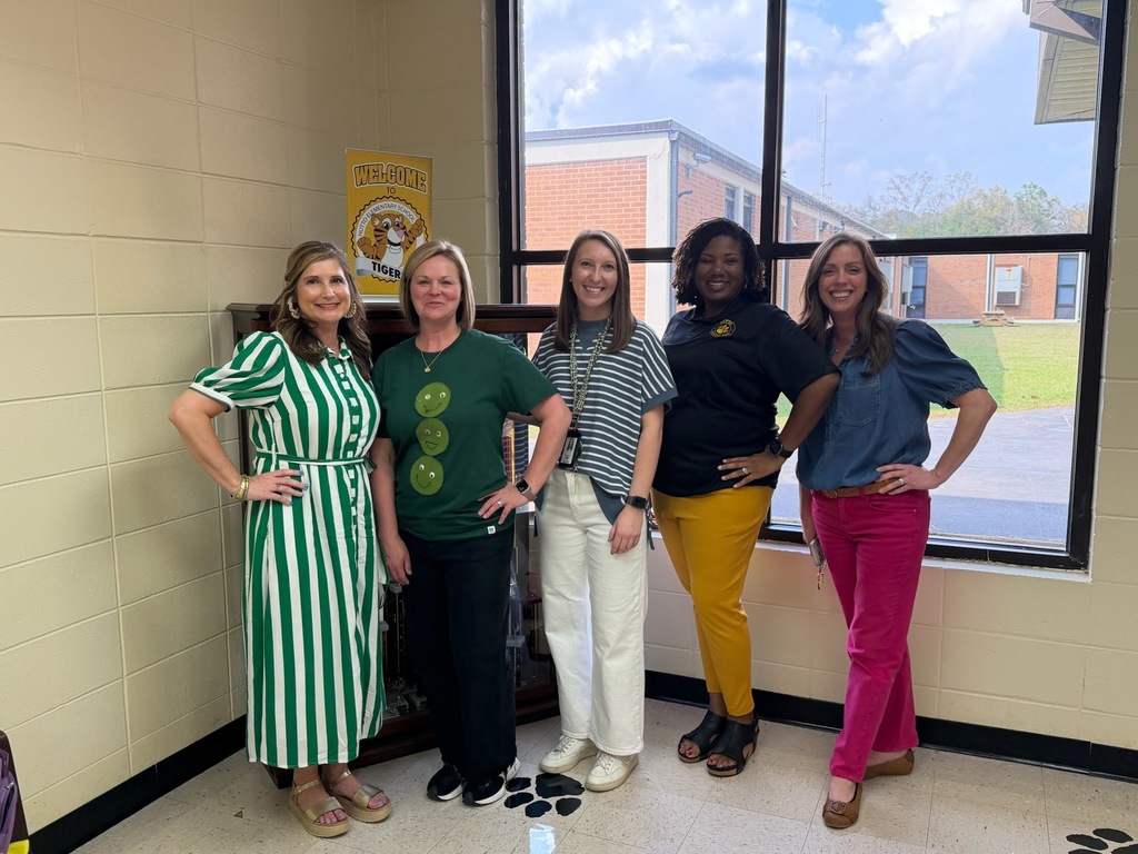 A group of school staff members gathered indoors at a school, smiling for a group photo.