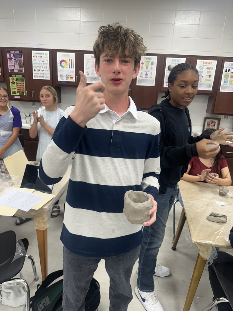 8th Grade student showing his clay cup.