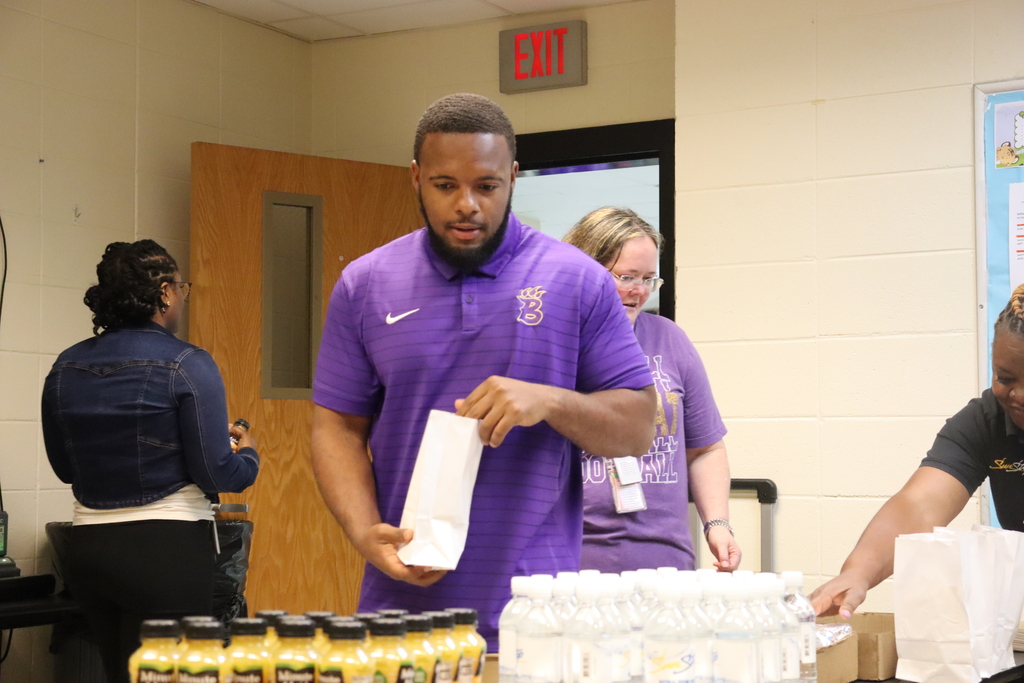 Staff member picks up breakfast while others help serve during a teacher appreciation event.