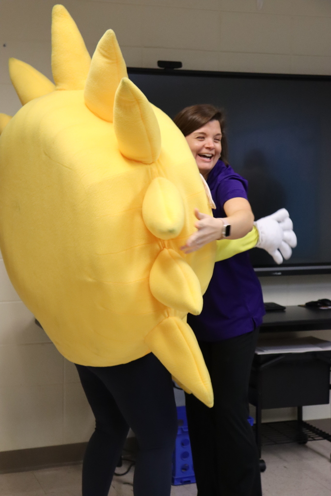 Sunny the SunStop mascot hugs a smiling staff member during a teacher appreciation visit.