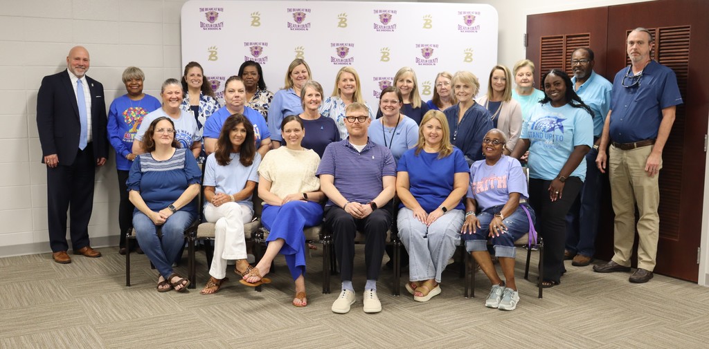 Staff members wearing blue pose for a picture