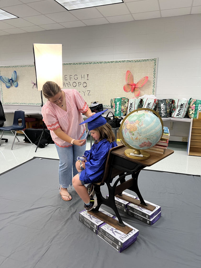 Bearcat Broadcasting member, Emsleigh Glass, helps a West Bainbridge Primary Kindergarten student with her cap and tassel.