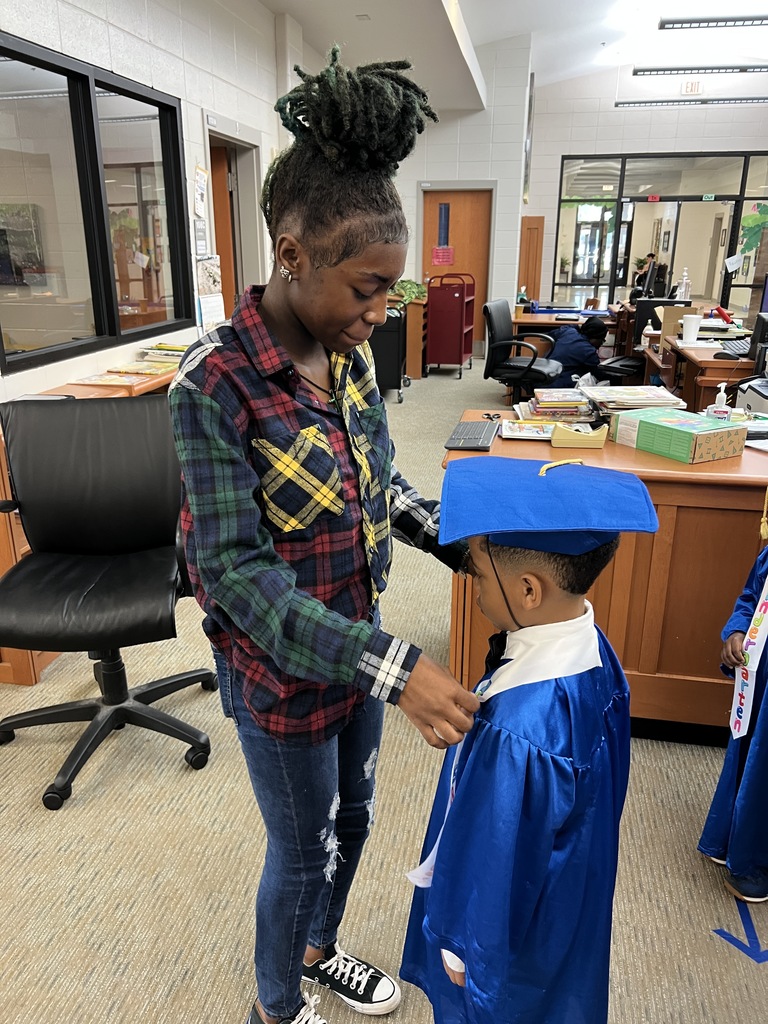 Bearcat Broadcasting student, Joy Mills, assists a Jones Wheat Primary Kindergarten student with his cap and gown.