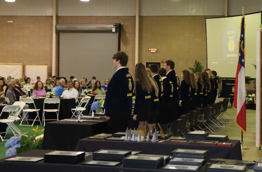Bainbridge FFA members line up during the ceremony as awards and recognitions are displayed in the foreground.