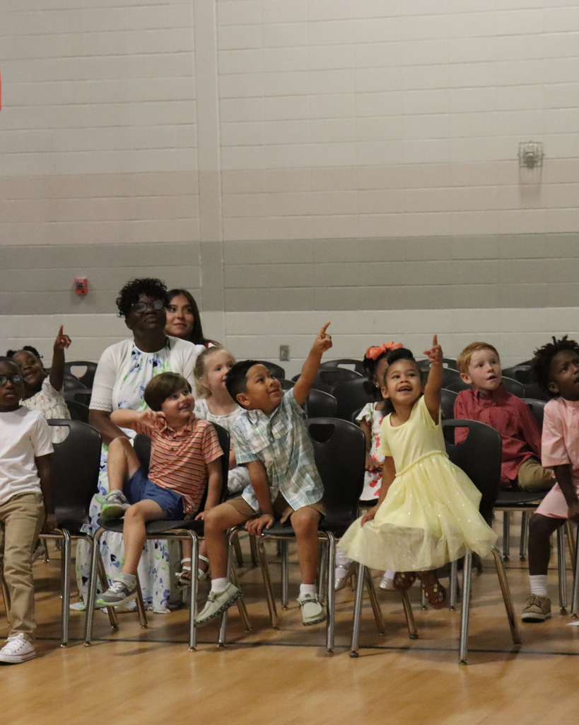 Pre-K students point excitedly during an interactive moment in the awards program while teachers supervise nearby.