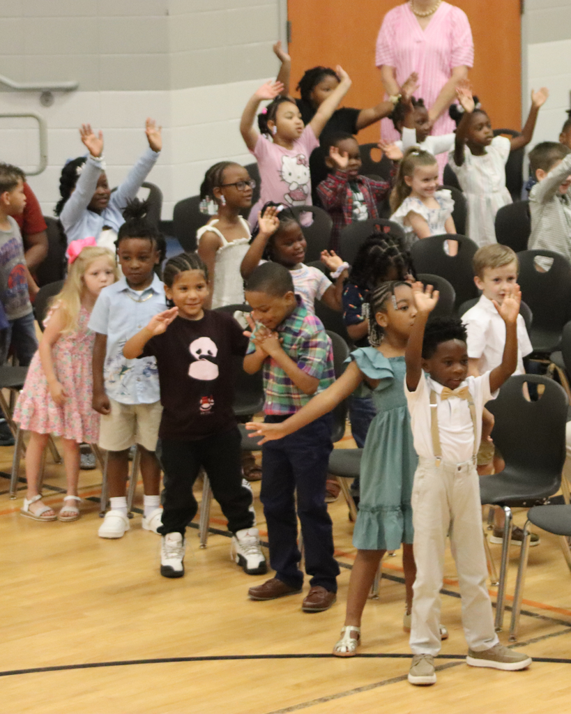 Pre-K students raise their hands and participate in a group activity during the awards program.