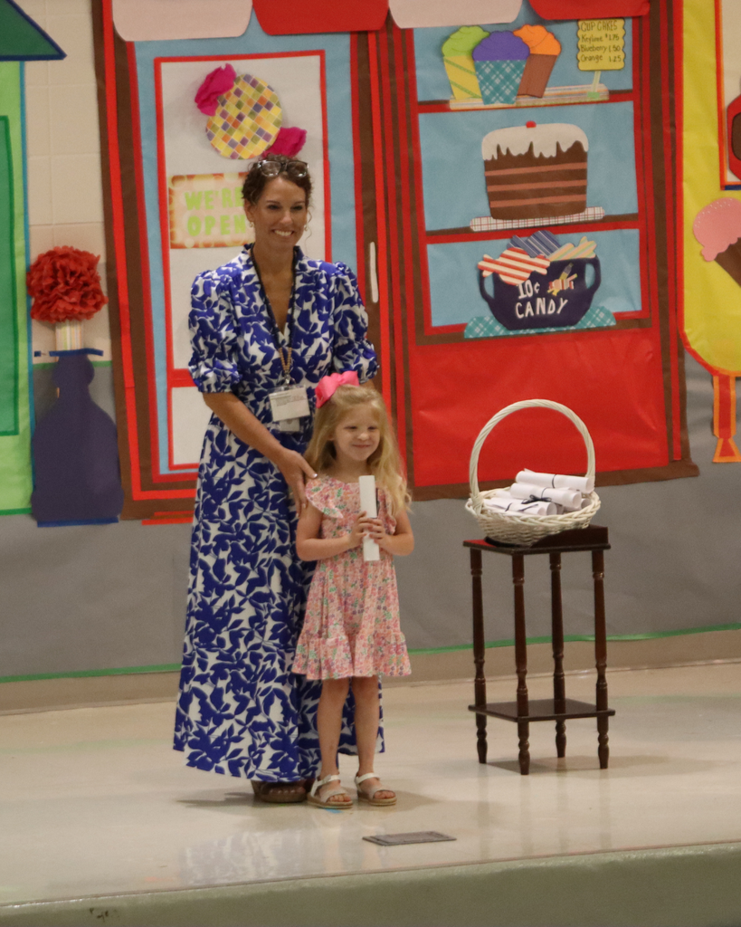 A Pre-K student poses with her certificate and teacher on stage during the JWP awards program.