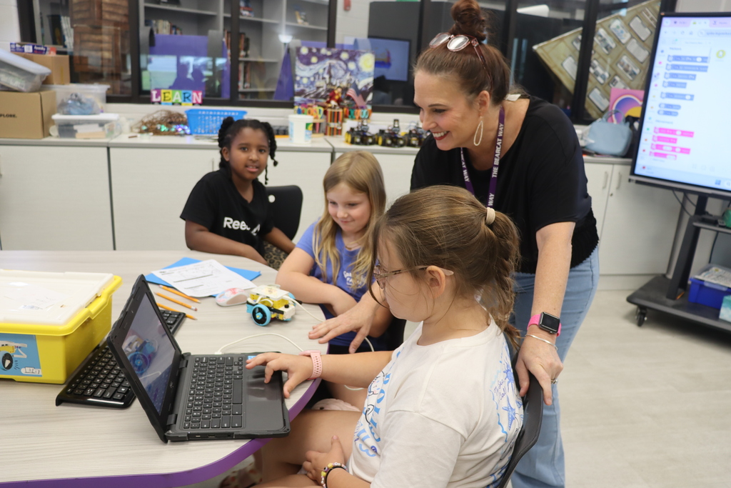 A teacher guides students as they learn coding and robotics during Summer STEM Camp.