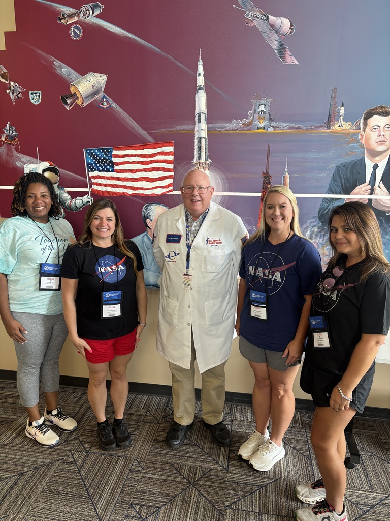 NASA HUNCH educators pose with a retired NASA electrical engineer in front of a space exploration mural at the U.S. Space & Rocket Center.