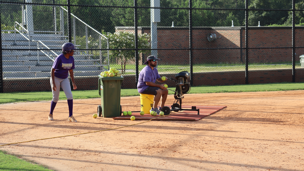 Softball player and coach work on batting practice.