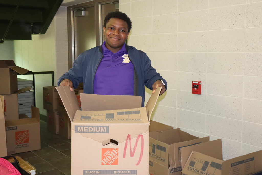A smiling Bearcat Blitz volunteer organizes cardboard boxes during the event.