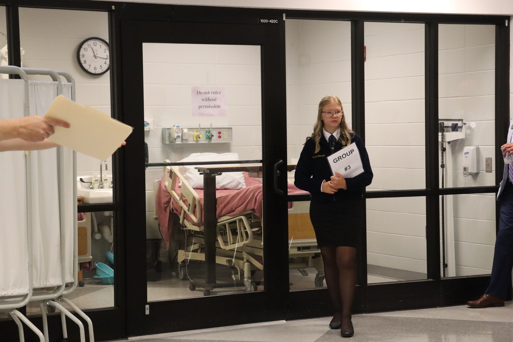 IMG_1092.JPG: A student guide welcomes a tour group to a healthcare learning lab.