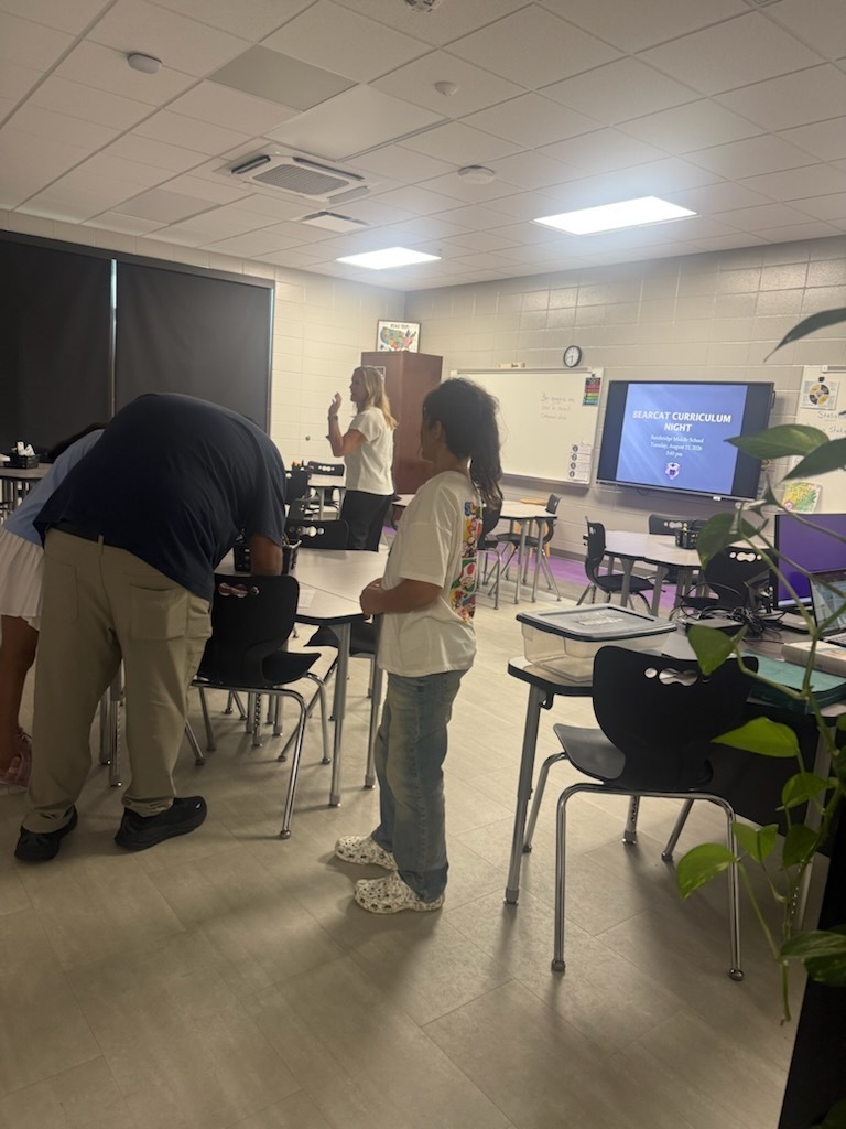 parents and teachers standin in a classroom for curriculum night