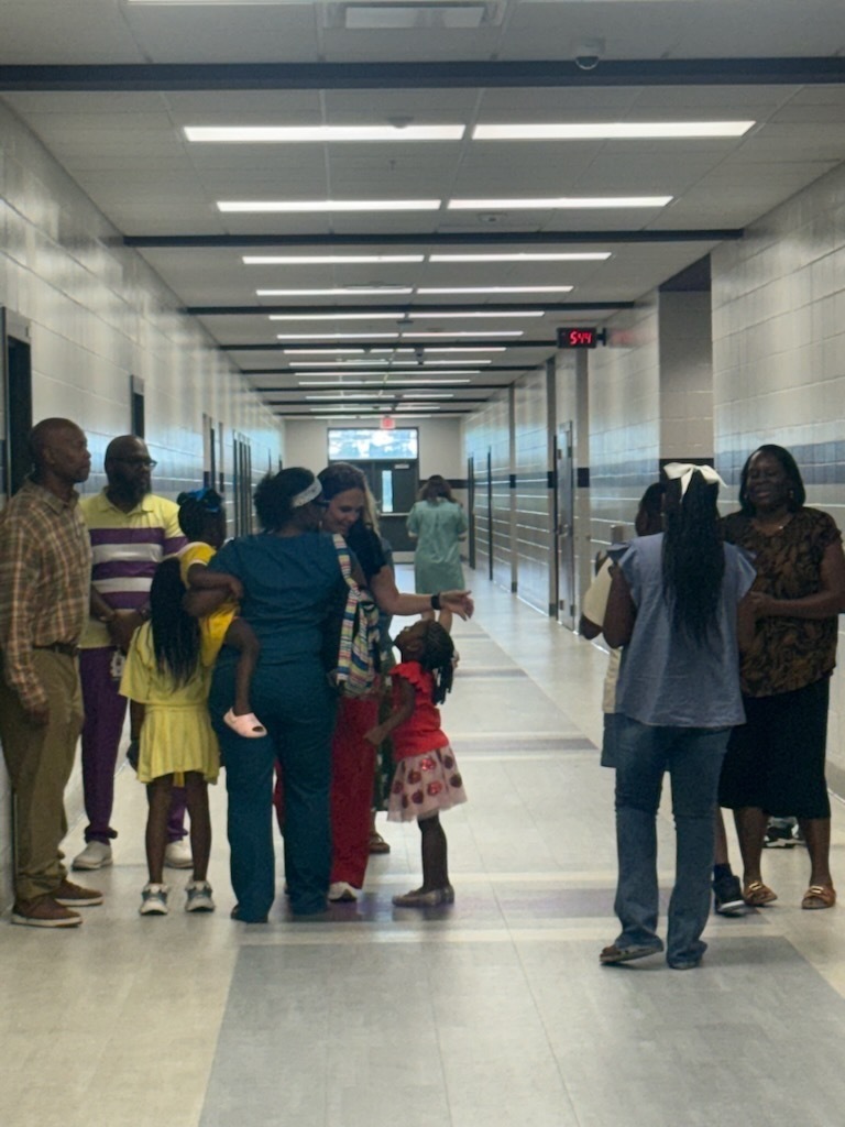 parents and teachers embrace in a hall