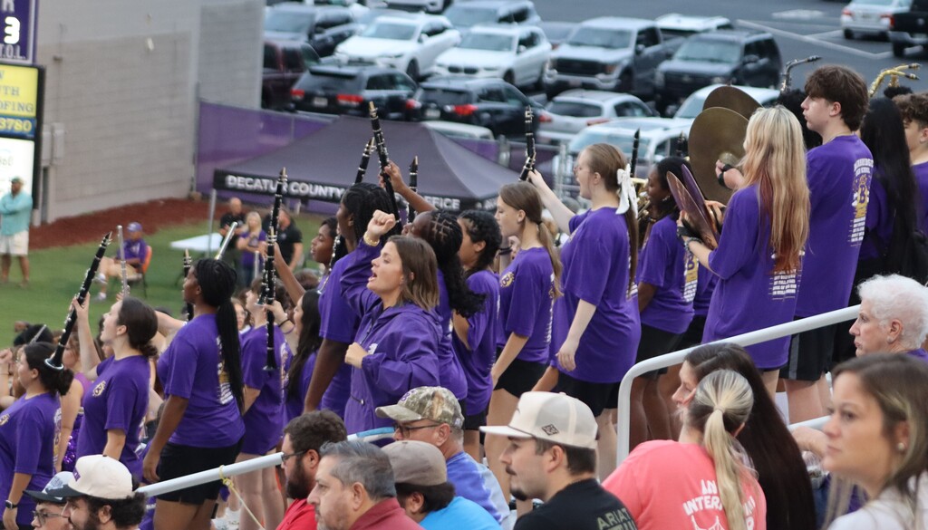 Bainbridge High School band members cheer with instruments in the stadium stands.