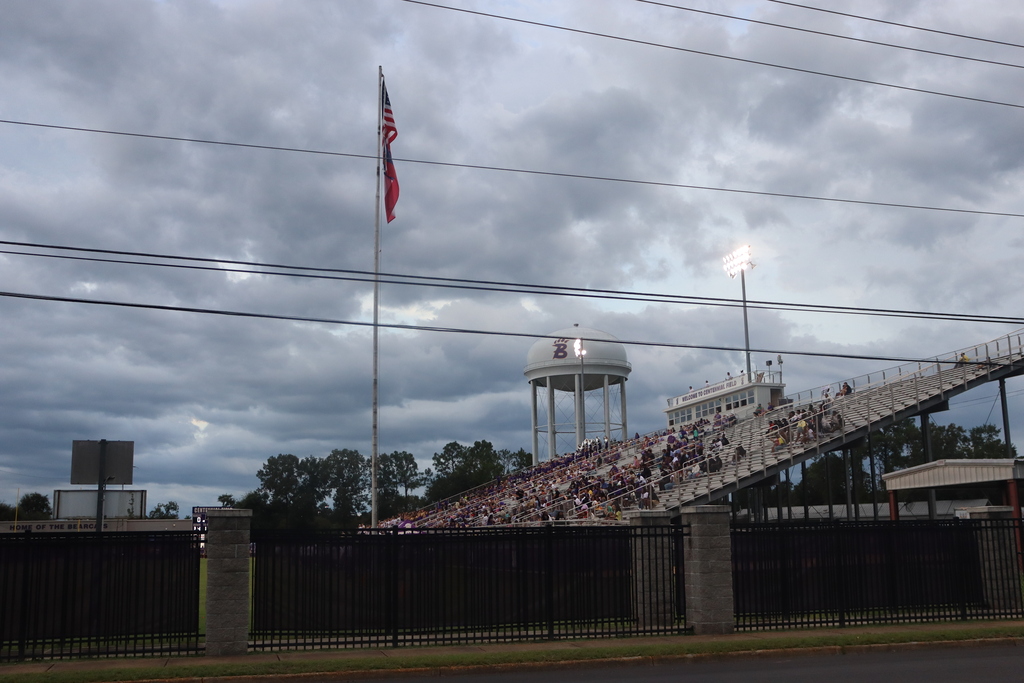 Bainbridge High School stadium under cloudy skies with the Bearcat water tower and fans in the stands.