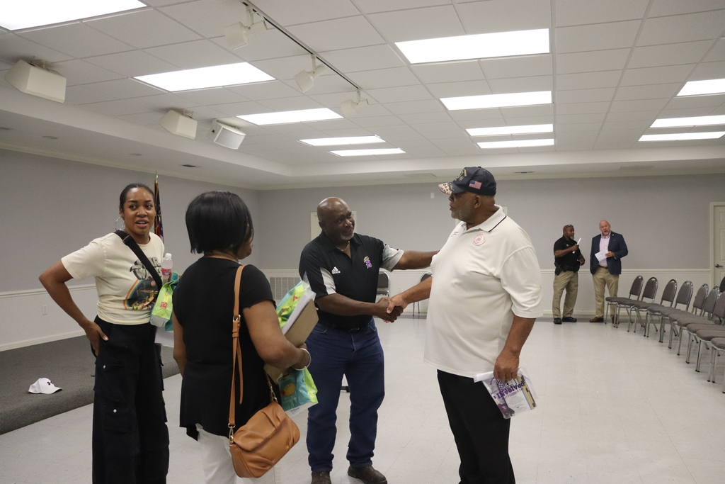 community members particpate in event at community center, engaging in conversation and shaking hands